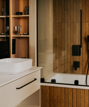 Łazienka z szafkami oraz wanną w zabudowie z białą umywalką nablatową