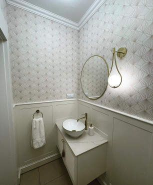 Łazienka z frontami ażurowymi oraz tapetą na ścianie i złotą lampą wiszącą