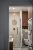 Łazienka z prysznicem, drewnianą szafką wiszącą, suszarką bębnową oraz pralką