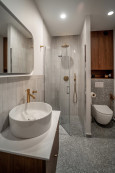 Nowoczesna łazienka z prysznicem walk-in oraz okrągłą umywalką nablatową i drewnianą szafką