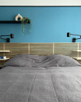 Sypialnia z drewnianym zagłówkiem oraz niebieskim kolorem ścian