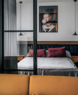 Sypialnia za szklanymi drzwiami z tapicerowanym zagłówkiem oraz stylowym obrazem na ścianie
