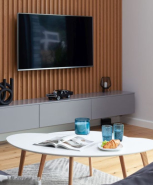 Eleganckie lamele drewniane stanowią tło dla telewizora w salonie