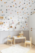 Nowoczesny pokój dziecięcy z tapetą w kropki na ścianie, szafą stojącą oraz stolikiem