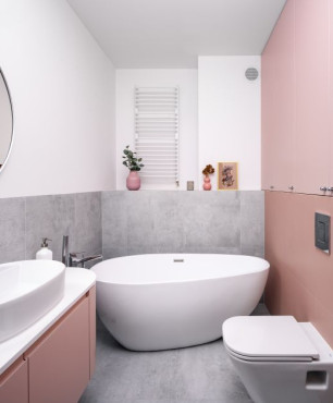 Łazienka w pastelowych kolorach z wanną wolnostojącą oraz z szarymi, wielkoformatowymi płytkami na ścianie