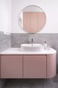 Łazienka z szafką wiszącą z różowym frontem oraz białą umywalką nablatową