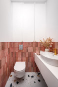 Kontrastowa łazienki z płytkami na ścianie w kolorze czerwonym oraz podłogą lastryko