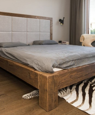 Piękne łóżko w drewnianej oprawie z drewnianymi panelami na podłodze