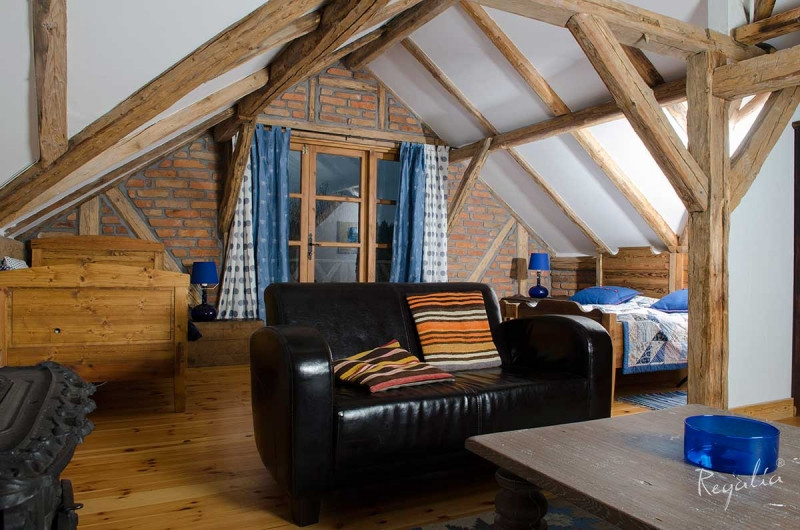Sypialnia z salonem w stylu rustykalnym z drewnianymi belkami na suficie