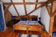 Sypialnia z drewnianymi belkami na suficie oraz z łóżkiem w drewnianej ramie