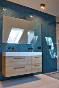 Duża łazienka z wbudowanym lustrem w ścianę oraz z niebieskimi płytkami ułożonymi w jodełkę na ścianie