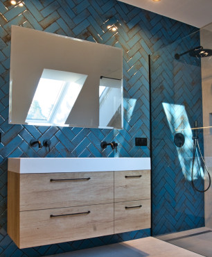 Duża łazienka z wbudowanym lustrem w ścianę oraz z niebieskimi płytkami ułożonymi w jodełkę na ścianie