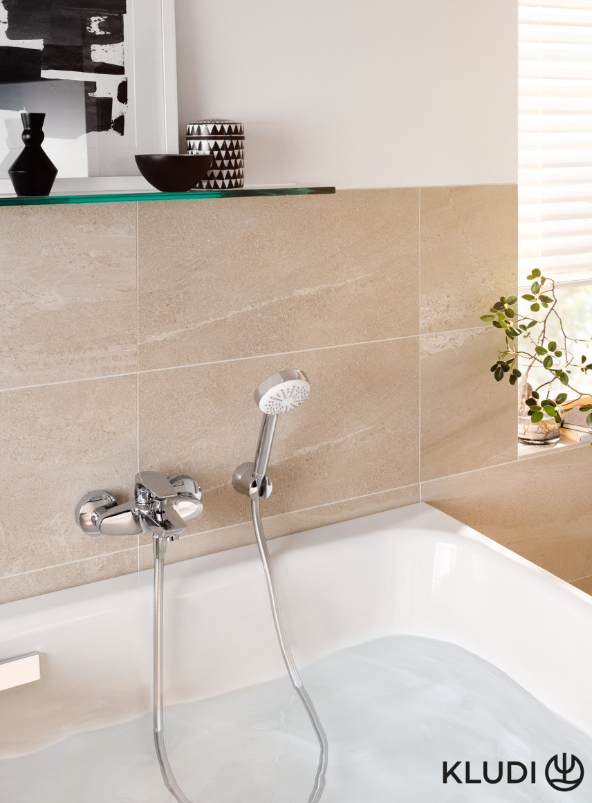 Klasyczna łazienka z beżowymi płytkami na ścianie oraz z wanną i srebrną armaturą łazienkową