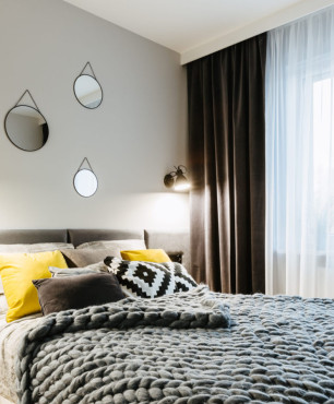 Mała sypialnia w stylu skandynawskim z tapicerowanym łóżkiem w kolorze szarym