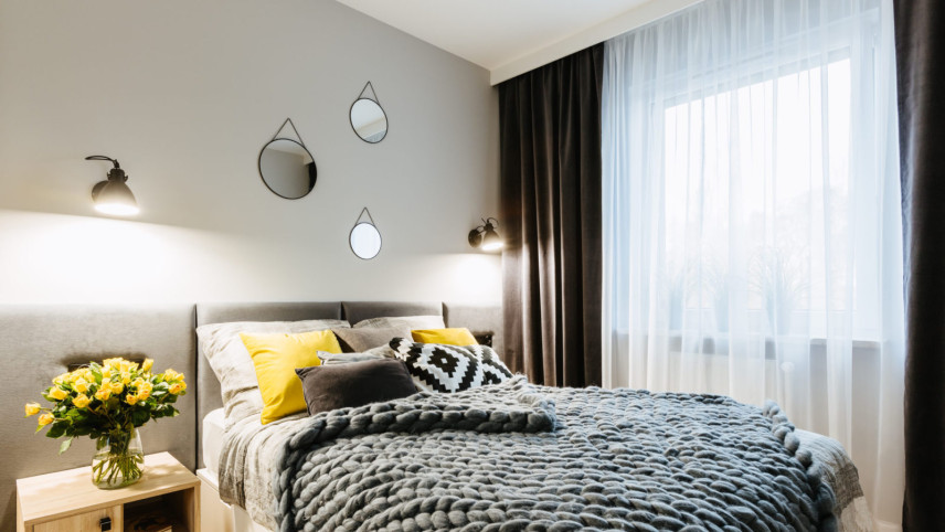 Mała sypialnia w stylu skandynawskim z tapicerowanym łóżkiem w kolorze szarym