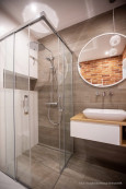 Łazienka z prysznicem narożnym oraz odpływem liniowym i imitacją drewnianych płytek na ścianie
