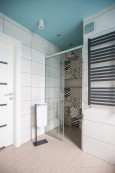 Łazienka z białymi i brązowymi płytkami oraz prysznicem z drzwiami przesuwnymi