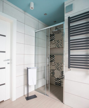 Łazienka z białymi i brązowymi płytkami oraz prysznicem z drzwiami przesuwnymi