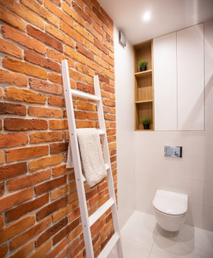 Mała łazienka z ceglaną ścianą oraz białą muszlą wiszącą