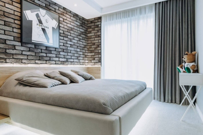 Sypialnia z cegłą na ścianie oraz z łóżkiem drewnianym kontynentalnym