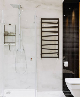 Łazienka z prysznicem i białymi płytkami na podłodze i ścianie oraz z czarnym kaloryferem