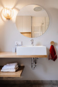 Nowoczesna łazienka z okrągłym lustrem oraz kinkietem na ścianie
