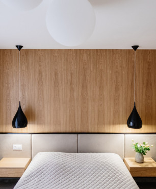 Sypialnia z drewnem na ścianie oraz łóżkiem kontynentalnym z tapicerowanym zagłówkiem