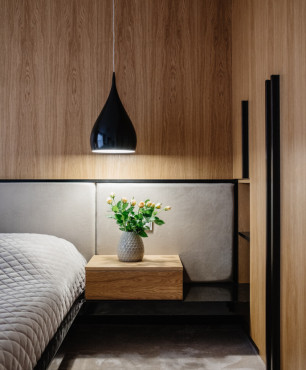Sypialnia z drewnem na ścianie oraz lampą wiszącą z czarnym kloszem