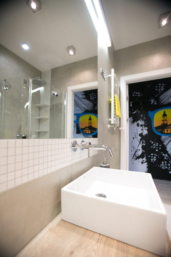 Nowoczesna łazienka z kwadratową umywalką stojącą oraz prostokątnym lustrem zamontowanym do ściany
