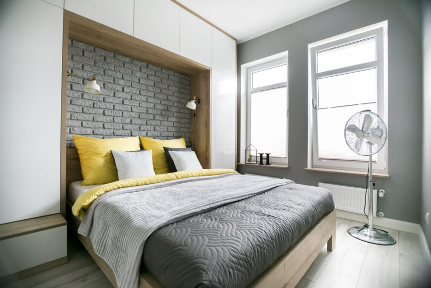 Mała sypialnia z biało-drewnianą zabudową nad łóżkiem