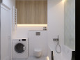 Łazienka z pralką, wanną w zabudowie, muszlą wiszącą oraz białymi płytkami na ścianie