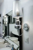 Łazienka w stylu glamour z kinkietem montowanym przy prostokątnym lustrze