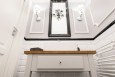 Modna toaleta z białą szafką stojącą z drewnianym blatem oraz z czarnym, kryształowym żyrandolem