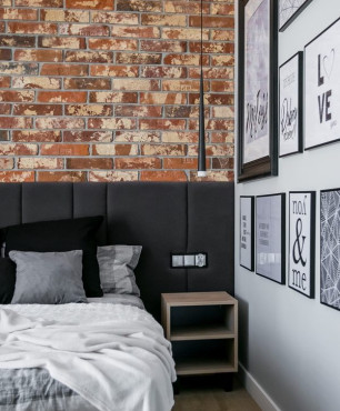 Sypialnia w stylu industrialnym z cegłą na ścianie oraz z tapicerowanymi panelami