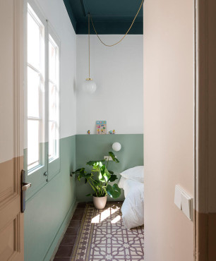 Sypialnia z biało-zielonym kolorem farby na ścianie oraz ze wzorzystymi płytkami na podłodze