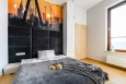 Sypialnia z dużym, kontynentalnym łóżkiem oraz z panelami tapicerowanymi w kolorze czarnym