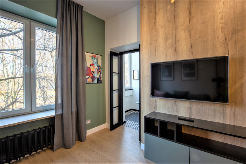 Salon z drewnem i telewizorem na ścianie oraz panelami na podłodze