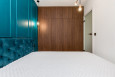 Sypialnia z drewnianą szafą w zabudowie pod sufit oraz z turkusowym kolorem ścian ze sztukaterią