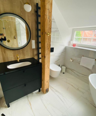 Łazienka z czarną szafką stojącą z umywalką podblatową, muszlą wiszącą oraz owalną wanną