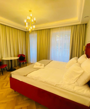 Projekt sypialni hotelowej z dużym, tapicerowanym łóżkiem w kolorze bordowym