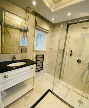 Mała łazienka w hotelu butikowym z lustrem, prysznicem oraz szafką stojącą z umywalką podblatową