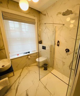 Mała łazienka hotelowa z prysznicem walk-in oraz oknem