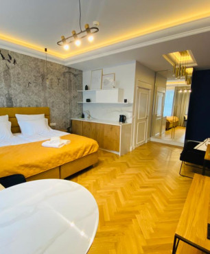 Nowoczesna sypialnia hotelowa z granatowym kolorem na jednej ścianie ze sztukaterią oraz z żółtym łóżkiem kontynentalnym