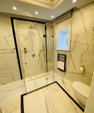 Łazienka hotelowa z gresowymi płytkami na ścianie i podłodze z prysznicem, oknem i sufitem podwieszanym
