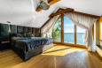 Piękna sypialnia z czarnymi tapicerowanymi panelami na ścianie oraz cudownym widokiem na jezioro