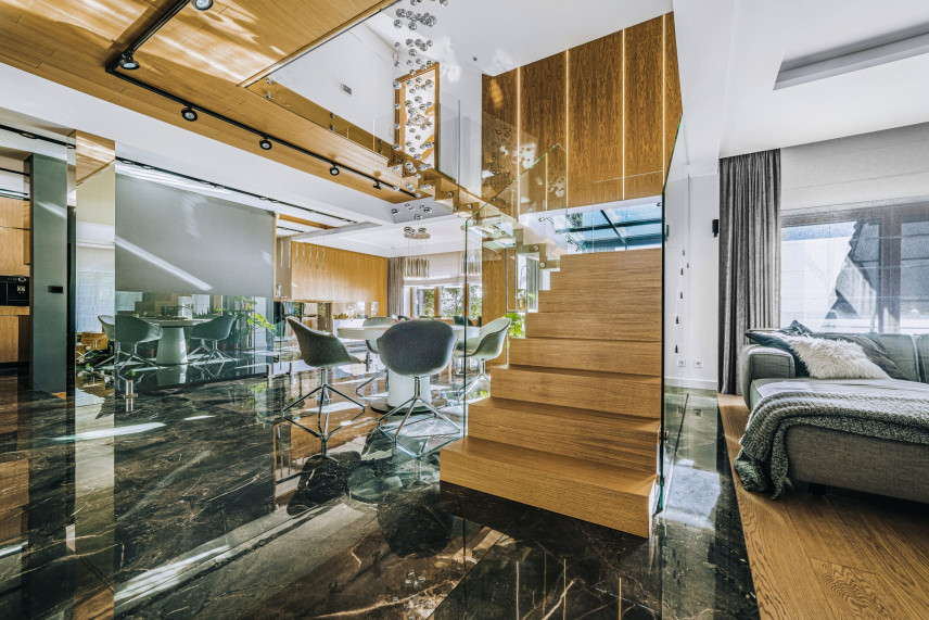 Widok na parter w domu jednorodzinnym z drewnianymi schodami oraz szklaną balustradą
