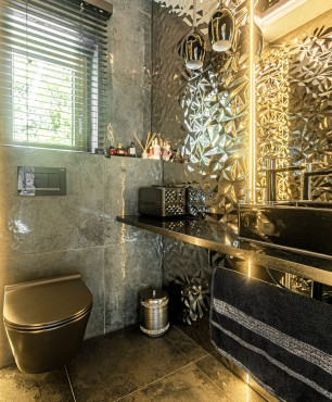 Nowoczesna łazienka ze złotym akcentem na ścianie oraz z czarną muszlą wiszącą