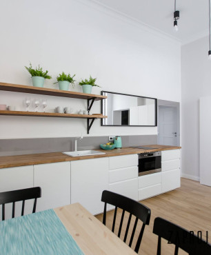 Kuchnia otwarta połączona z jadalnią oraz jasnymi panelami na podłodze