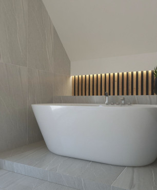 Projekt łazienki na poddaszu z ceramiczną wanną wolnostojąca, drewnianymi żaluzjami oraz drewnianym lamelem z podświetleniem Led