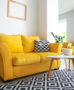Żółta sofa z biało-czarnym dywanem